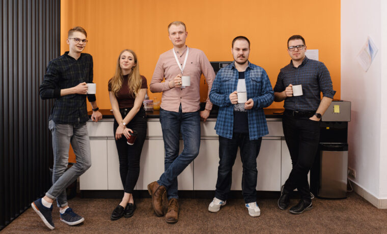 Happy diverse colleagues have fun at lunch break in office, smiling multiracial employees laugh and drinking coffee.
